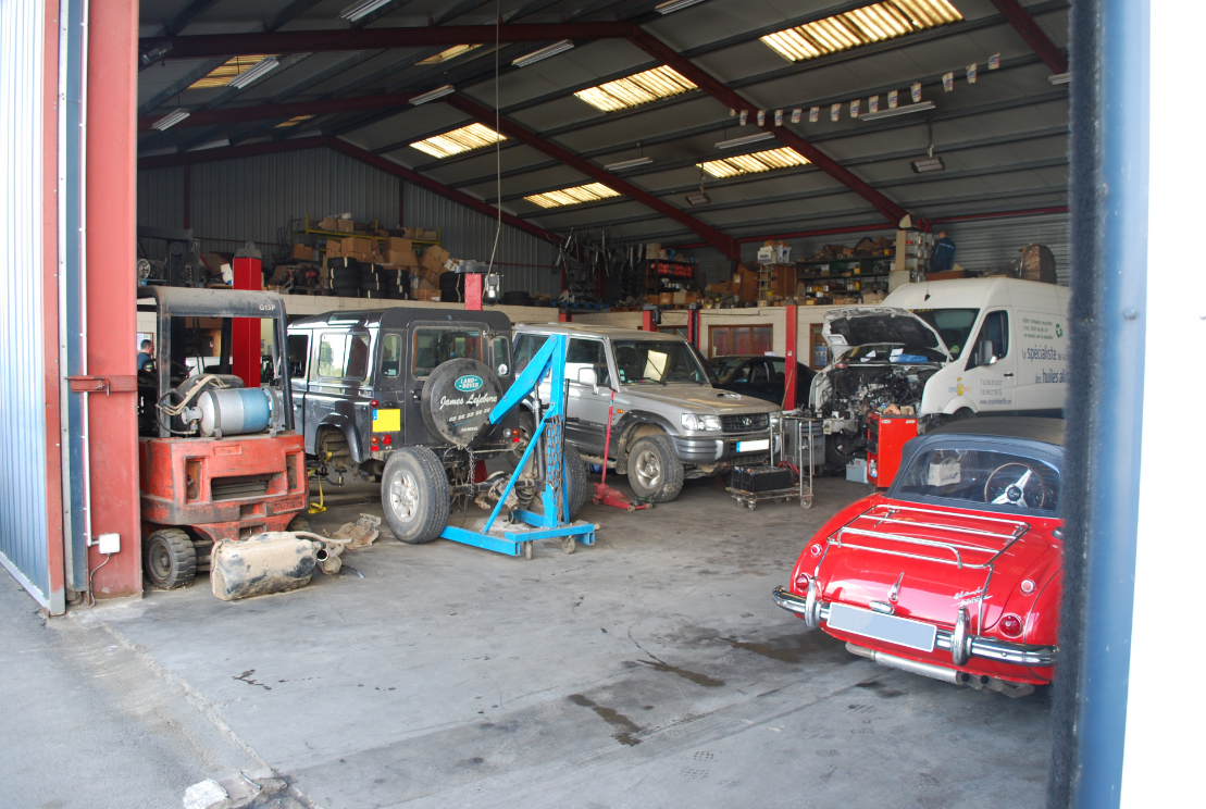 Tracteur, Land Rover Defender et voiture de collection réunis dans l'atelier du garage Pointin à Roye