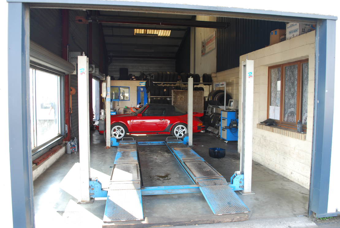 Porsche 911 rouge sur le pont élévateur de l'atelier du garage Pointin à Roye